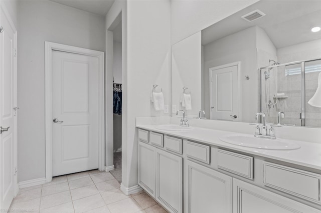 bathroom featuring tile patterned flooring, a sink, a shower stall, and double vanity