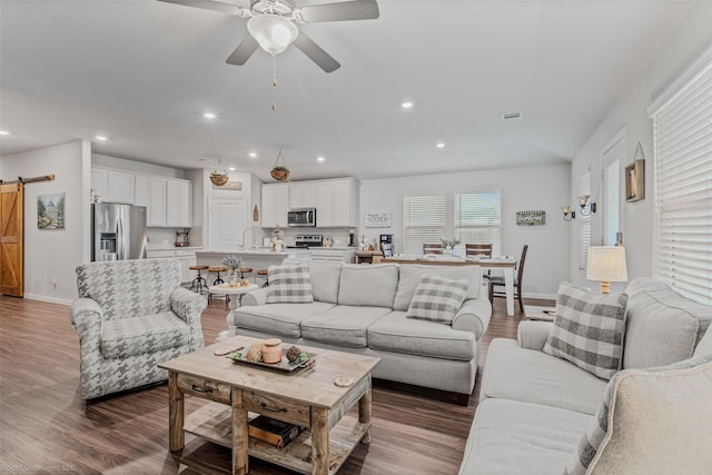 living room with a barn door, recessed lighting, wood finished floors, a ceiling fan, and visible vents