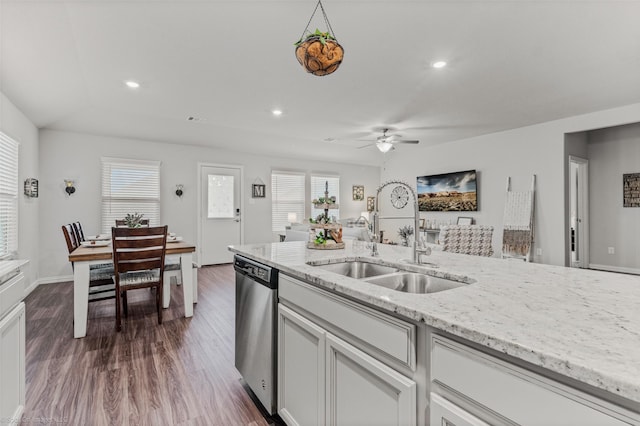 kitchen with light stone counters, recessed lighting, stainless steel dishwasher, dark wood-type flooring, and a sink