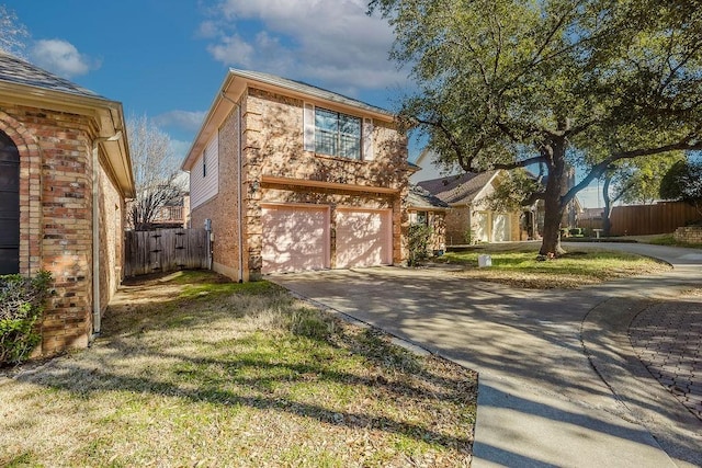 view of front of home with concrete driveway, brick siding, an attached garage, and fence