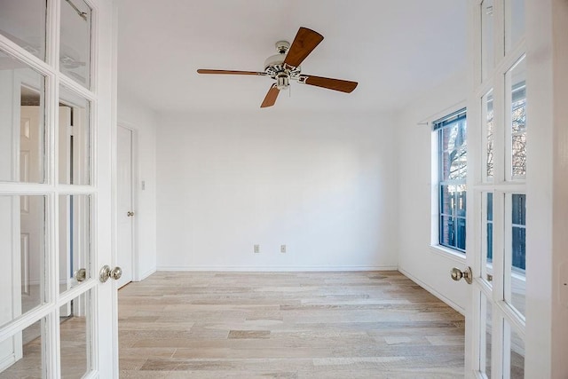 unfurnished room with light wood-type flooring, baseboards, a ceiling fan, and french doors