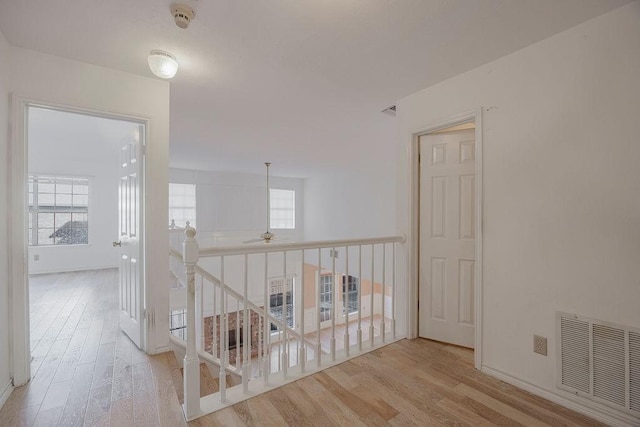 corridor featuring visible vents, wood finished floors, and an upstairs landing