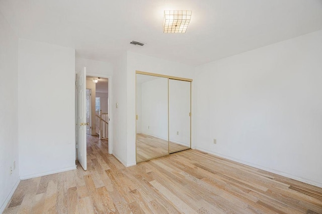 unfurnished bedroom with baseboards, a closet, visible vents, and wood finished floors