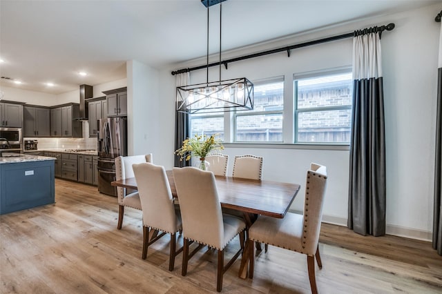 dining area with recessed lighting, light wood-style flooring, baseboards, and an inviting chandelier