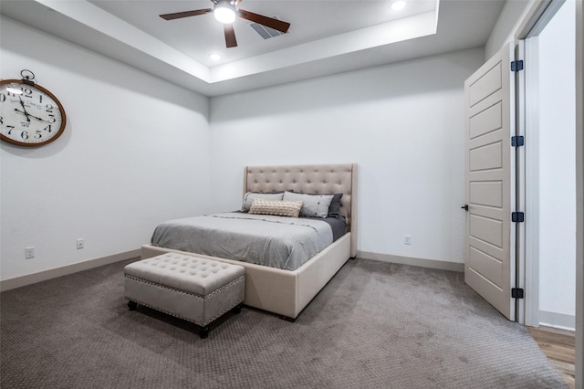 carpeted bedroom featuring recessed lighting, a raised ceiling, and baseboards