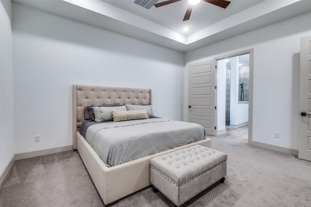 bedroom with light carpet, baseboards, a tray ceiling, and a ceiling fan