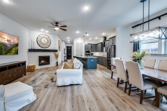 living room featuring light wood-style floors, ceiling fan, a fireplace, and recessed lighting