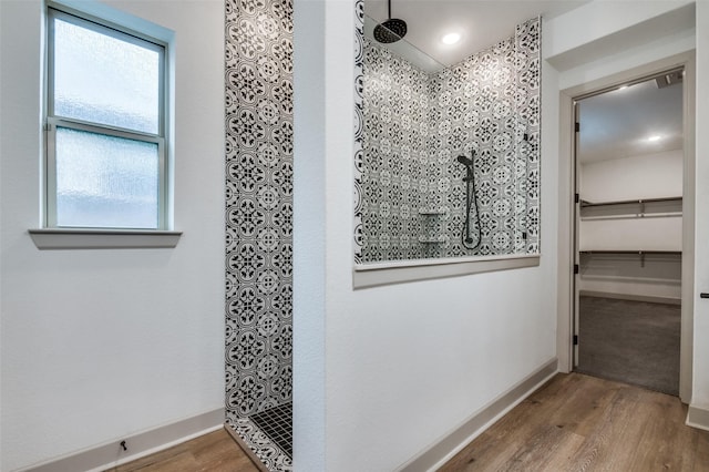 full bath with a spacious closet, baseboards, a walk in shower, and wood finished floors