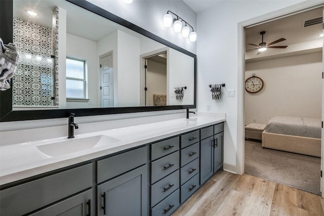 bathroom featuring double vanity, visible vents, a ceiling fan, wood finished floors, and a sink