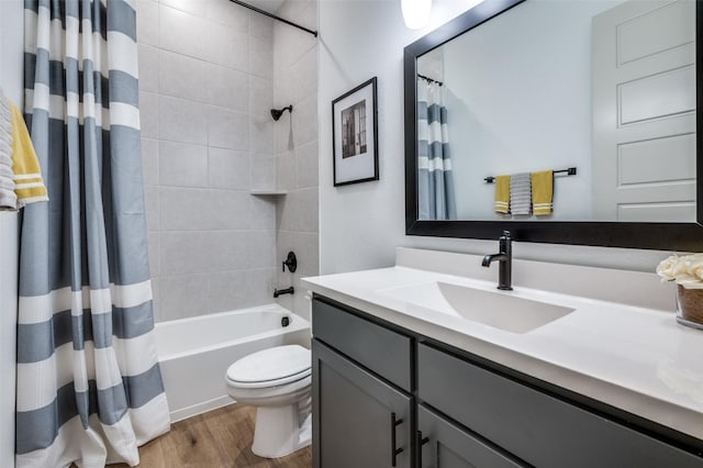 bathroom with toilet, shower / bath combo with shower curtain, wood finished floors, and vanity