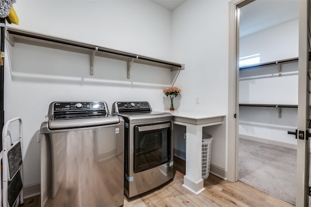 laundry area featuring light wood finished floors, laundry area, separate washer and dryer, and baseboards