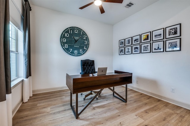 home office with light wood finished floors, baseboards, visible vents, and a ceiling fan