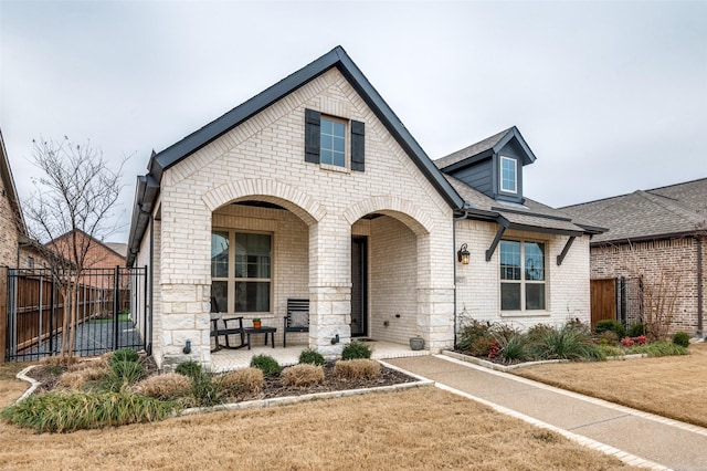 view of front of home featuring a shingled roof, a front yard, brick siding, and fence