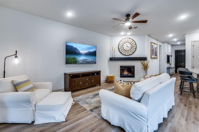 living area featuring a stone fireplace, recessed lighting, and light wood-style floors