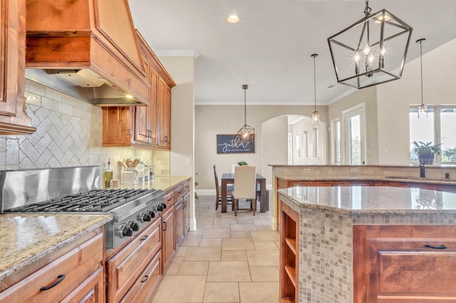 kitchen with arched walkways, light stone counters, stainless steel gas cooktop, decorative backsplash, and crown molding