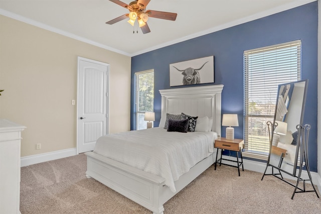 carpeted bedroom with a ceiling fan, crown molding, and baseboards