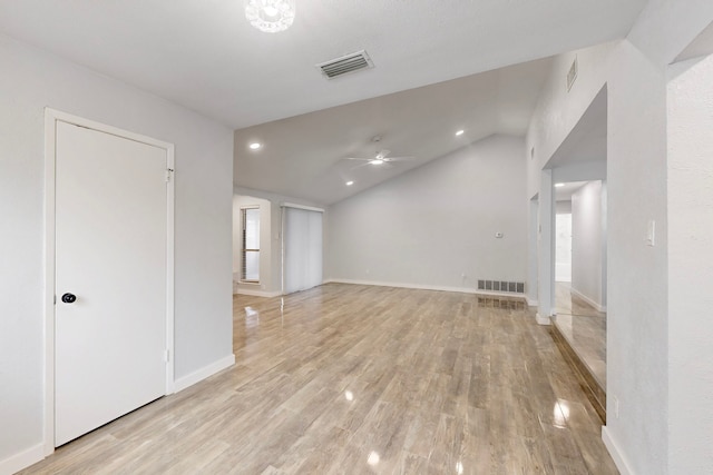 empty room featuring vaulted ceiling, light wood finished floors, visible vents, and a ceiling fan