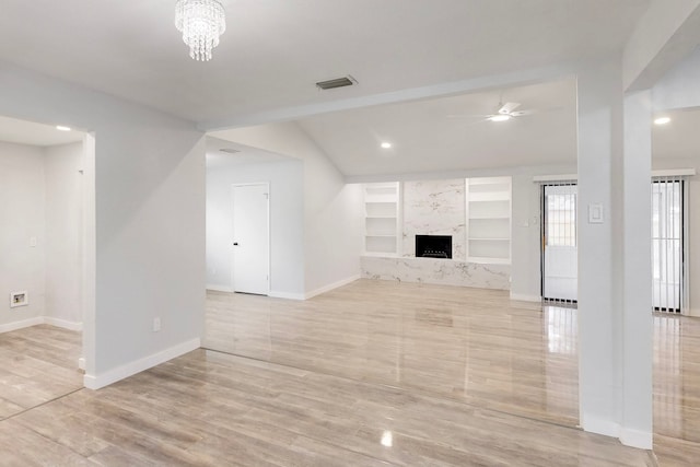 unfurnished living room with baseboards, visible vents, built in features, a fireplace, and ceiling fan with notable chandelier