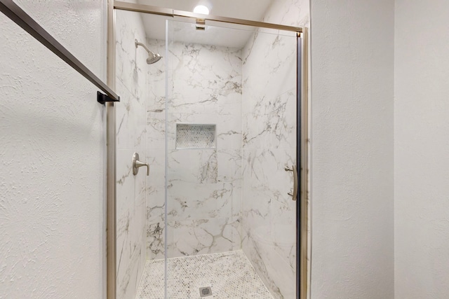 full bathroom featuring a textured wall and a marble finish shower