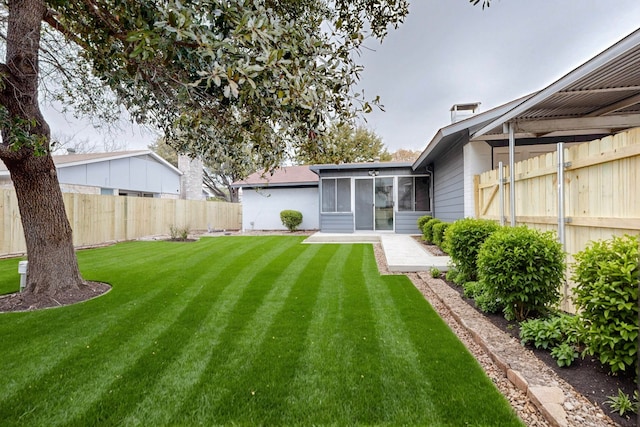 view of yard featuring a patio area, a fenced backyard, and a sunroom