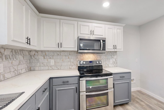 kitchen with stainless steel appliances, white cabinets, gray cabinetry, and tasteful backsplash