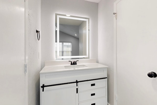 bathroom with a textured wall and vanity