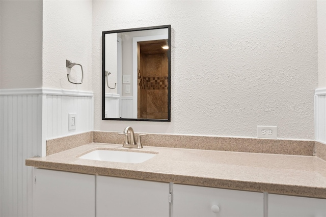 bathroom featuring a wainscoted wall, vanity, and a textured wall