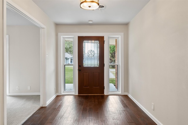 foyer entrance featuring visible vents, baseboards, and dark wood finished floors