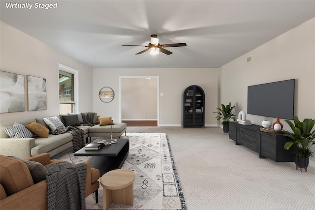 living area featuring visible vents, baseboards, a ceiling fan, and light colored carpet