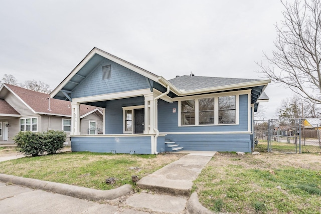 bungalow featuring a front yard, roof with shingles, and fence