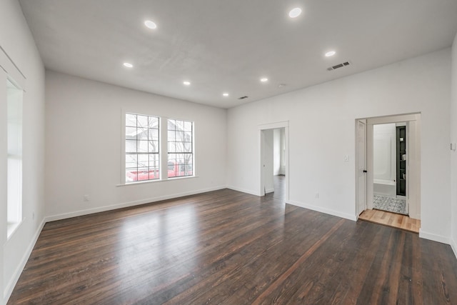 empty room with dark wood-style floors, baseboards, visible vents, and recessed lighting