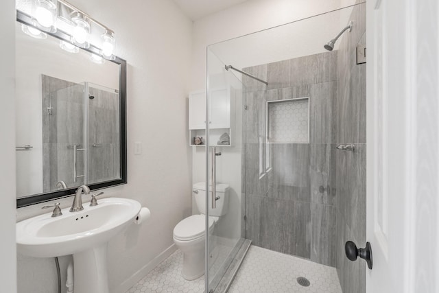 full bath featuring toilet, a shower stall, baseboards, and tile patterned flooring