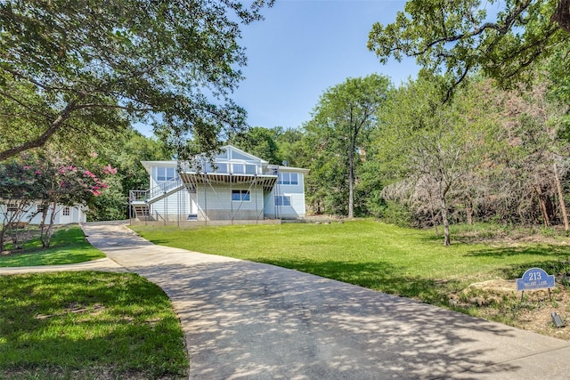 exterior space featuring a deck, stairway, a front lawn, and concrete driveway