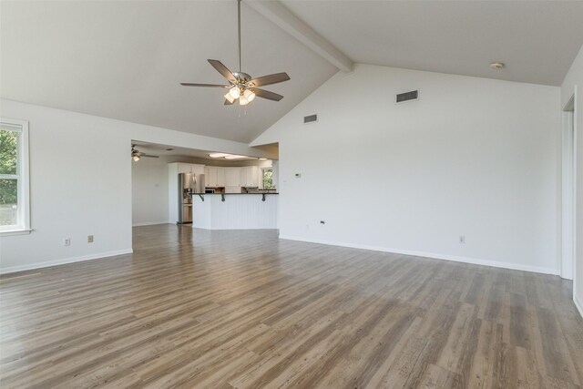 kitchen featuring a center island, dark countertops, open floor plan, white cabinetry, and a kitchen bar