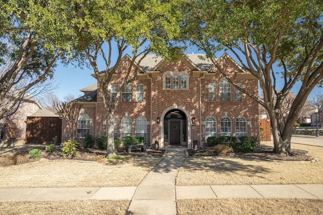 view of front of home featuring fence and brick siding