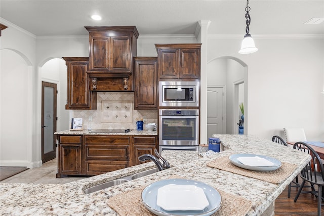 kitchen with dark brown cabinetry, visible vents, arched walkways, stainless steel microwave, and a sink