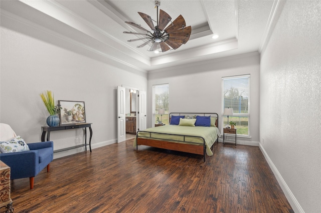 bedroom with a textured wall, dark wood-style flooring, baseboards, a tray ceiling, and crown molding