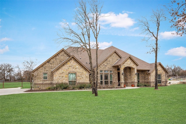 french provincial home featuring a shingled roof, brick siding, and a front lawn