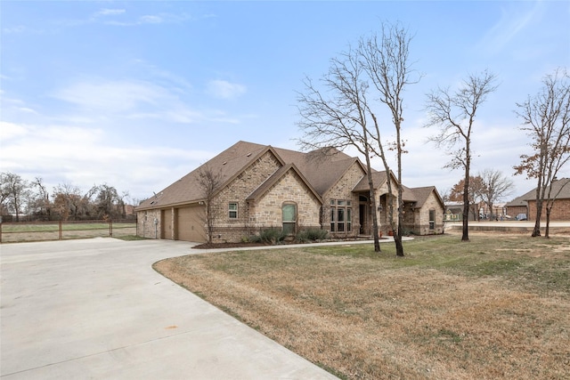 french country inspired facade with concrete driveway, stone siding, an attached garage, a front lawn, and brick siding