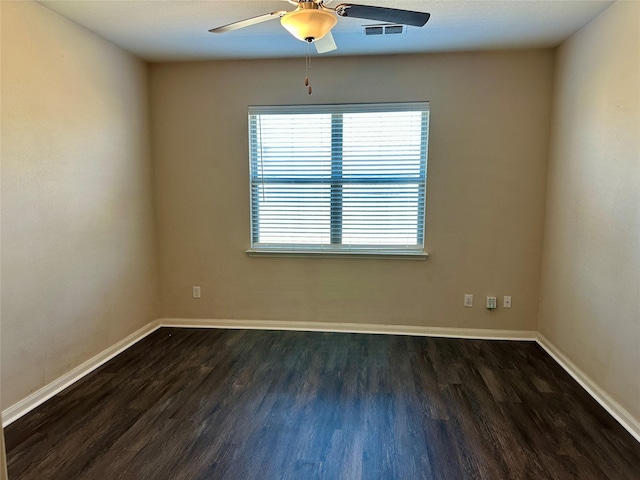 spare room featuring dark wood-type flooring, visible vents, and baseboards