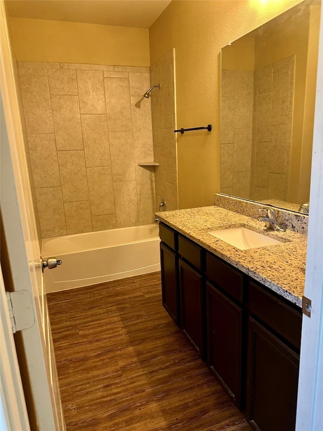 full bath with washtub / shower combination, vanity, and wood finished floors