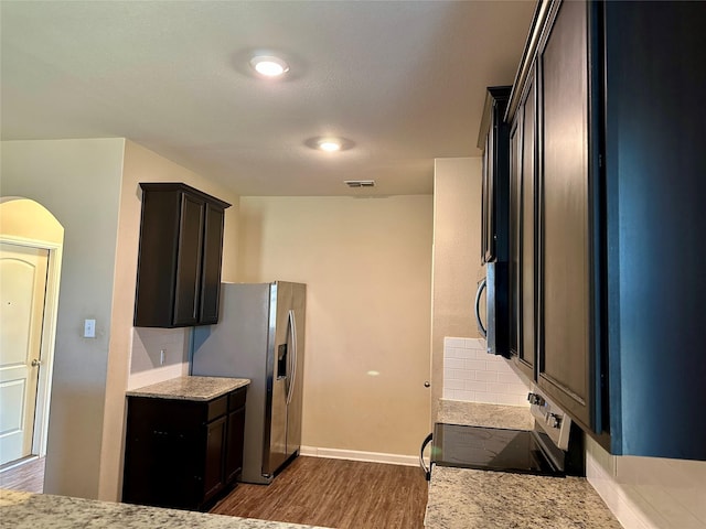 kitchen featuring light stone counters, stainless steel appliances, visible vents, decorative backsplash, and dark wood finished floors