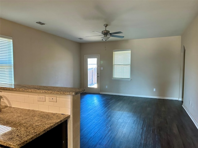 interior space with visible vents, dark wood finished floors, a ceiling fan, and baseboards