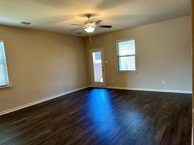 spare room with dark wood-style floors, ceiling fan, visible vents, and baseboards