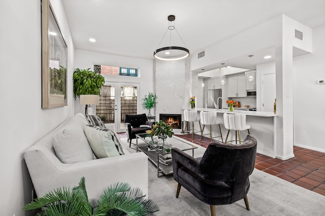 living area with french doors, recessed lighting, visible vents, a high end fireplace, and baseboards