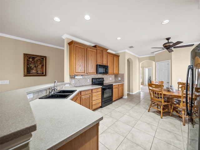 kitchen featuring arched walkways, a sink, light countertops, black appliances, and tasteful backsplash