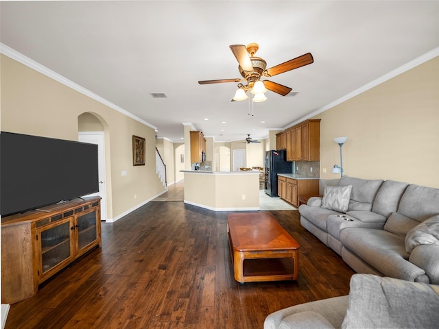 living area with baseboards, arched walkways, a ceiling fan, ornamental molding, and wood finished floors