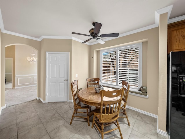 dining space featuring ornamental molding, arched walkways, ceiling fan with notable chandelier, and light tile patterned floors