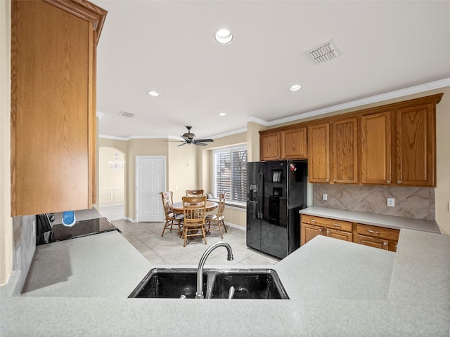 kitchen featuring ornamental molding, black fridge, a sink, and visible vents