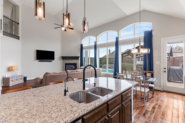 kitchen with light stone counters, a tiled fireplace, dark wood finished floors, and dark brown cabinetry